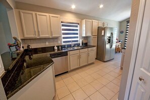 A kitchen with white cabinets, a stainless steel refrigerator, and a black countertop. - Mallory Paradise Apartment 4 Bedroom (Haines City)