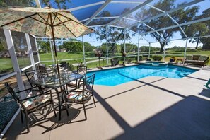 A covered outdoor area with a pool, glass tables, and chairs. - Mallory Paradise Apartment 4 Bedroom (Haines City)
