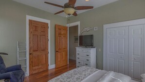 A bedroom with a bed, a ceiling fan, a dresser, and a television. - Camp Palms Indian Pass 2 Bedroom Apartment (Port St. Joe)