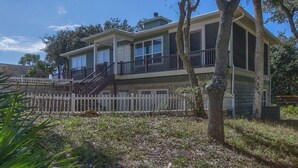A two-story house with a balcony, a white picket fence, and a tree in the foreground. - Camp Palms Indian Pass 2 Bedroom Apartment (Port St. Joe)