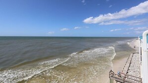 A beach with a wooden walkway leading to a building.