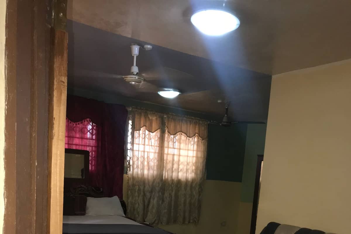 Una habitación con cama, sofá, una mesita y un ventilador de techo.