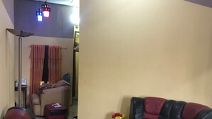 A living room with a sofa, ottoman, and a patterned rug. - Heritage Investments Hotel (Accra)