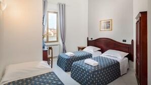 A hotel room with two beds, a wooden headboard, a small bedside table, a chair, a window with curtains, and a picture on the wall. - Casa Micol (Florence)