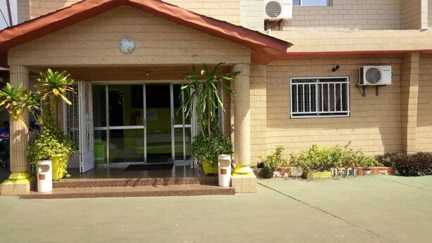 Un edificio con fachada de tejas, techo rojo y varias unidades de aire acondicionado.