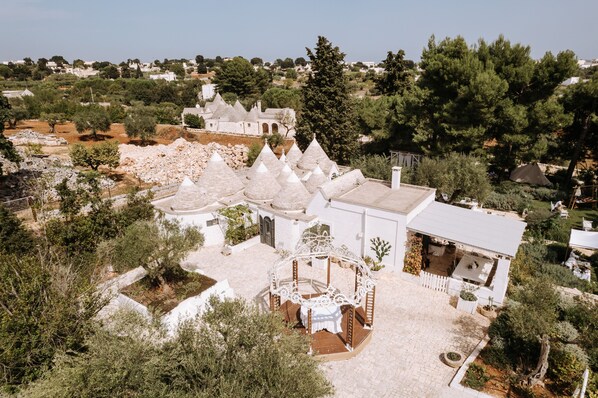 A white villa with conical roofs, a gazebo, and a garden. - Tenuta del Lauro (Locorotondo)