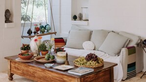 Una sala de estar acogedora con una mesa de centro de madera, un sofá blanco y una planta colgante.