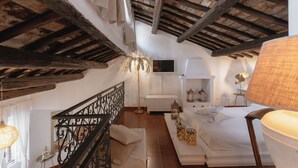 Quarto com teto de madeira, cama, mesas de cabeceira e televisão.