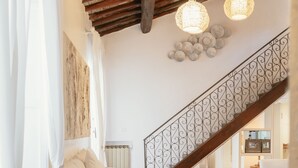 Uma sala de estar acolhedora com teto de madeira, um sofá branco, uma pequena mesa redonda e uma estátua de Buda.