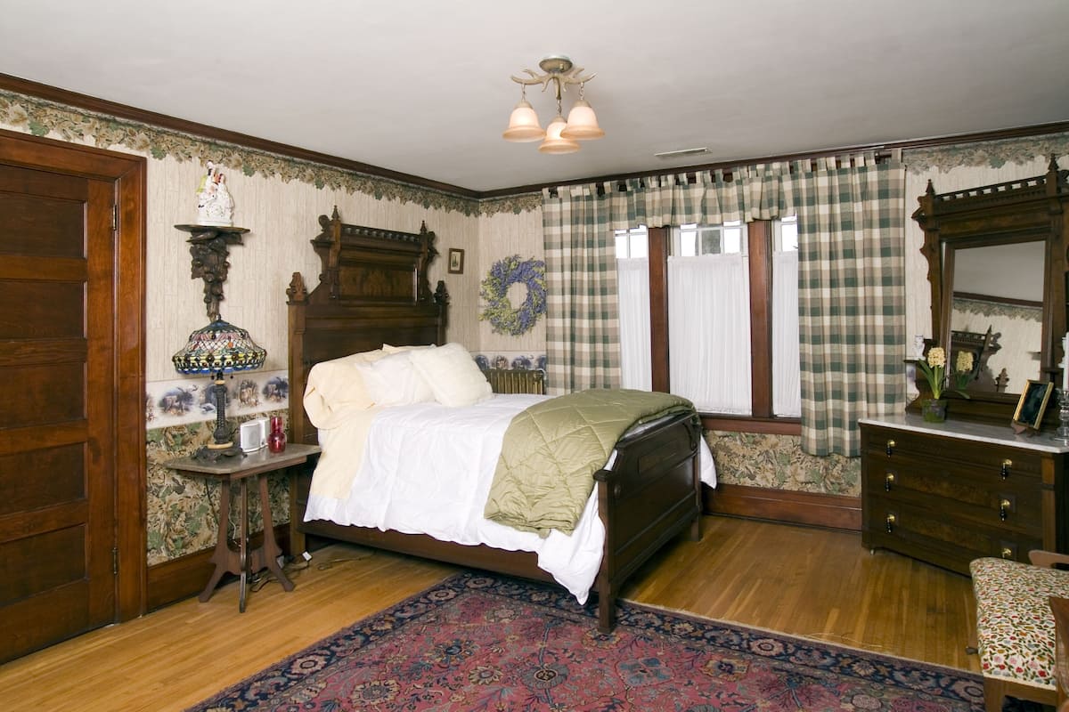 A traditional bedroom with a wooden bed, a nightstand, a dresser, and a mirror.