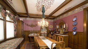 Une salle à manger avec une table en bois, des chaises, un lustre et un banc.
