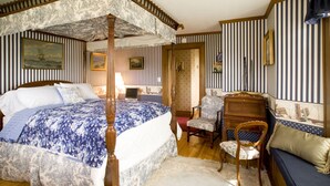 Une chambre à coucher avec un lit à baldaquin, un bureau, une chaise et un canapé.