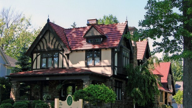 Un hôtel de style Tudor victorien, avec une façade en pierre, un toit recouvert de tuiles rouges et une enseigne devant l’entrée.