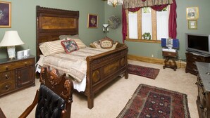 Une chambre à coucher de style traditionnel, avec un lit en bois, un lustre, une télévision et une fenêtre avec des rideaux.