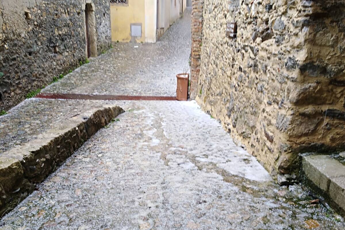 A cobblestone alley with stone walls on either side, leading to a building entrance.