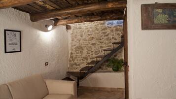 A cozy room with a stone wall, a wooden staircase, a framed picture, and a green plant.