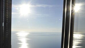 Vista a través de una ventana con cielo despejado y mar tranquilo.
