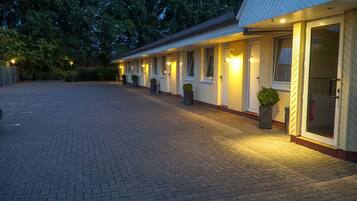 A row of motel rooms with individual doorways, each illuminated by exterior lighting.