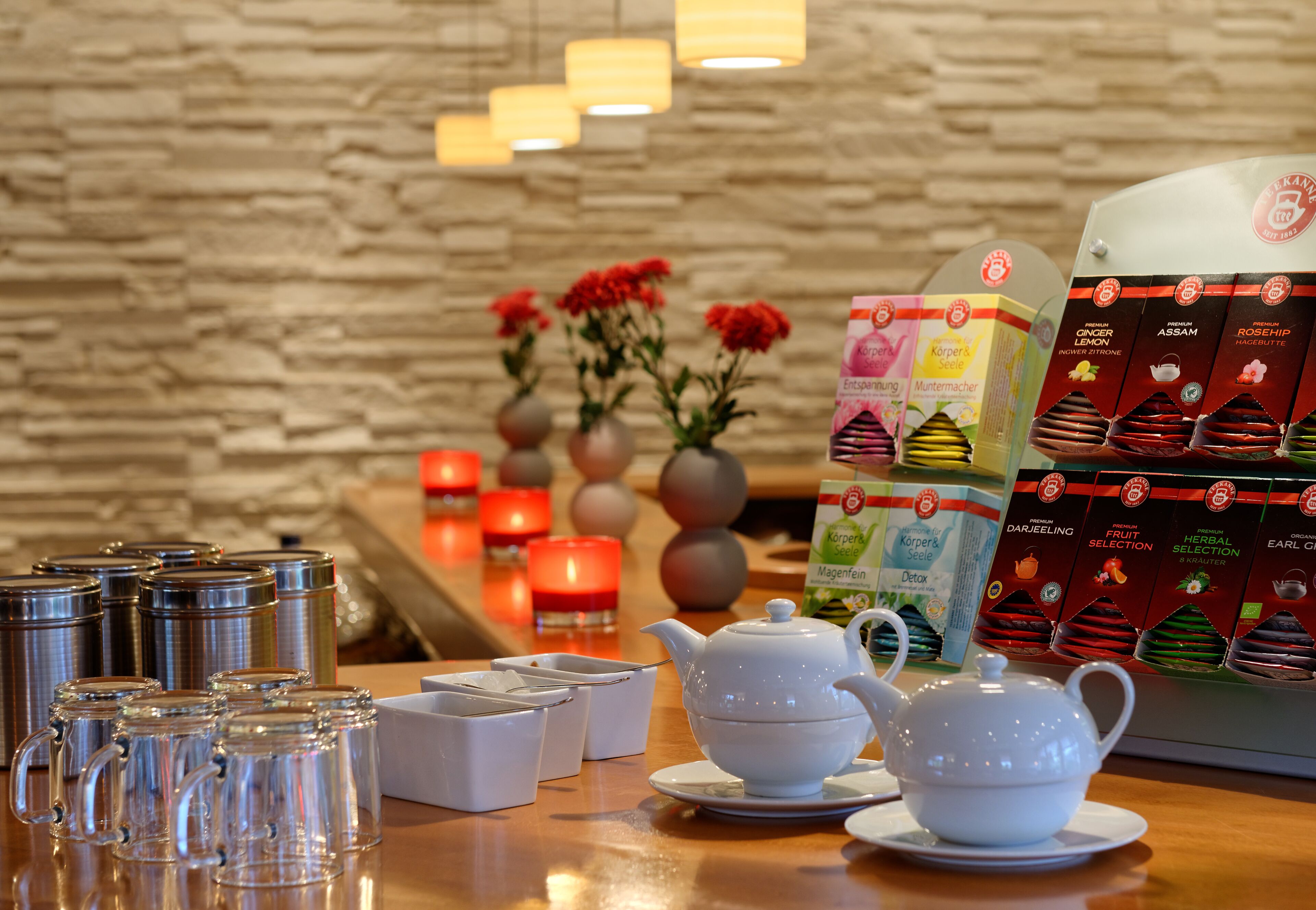A tea station with a teapot, cups, and a selection of herbal tea boxes.