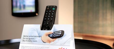 A remote control on a stand with a sign that reads "Better entertainment for our guests - Sky in every room."