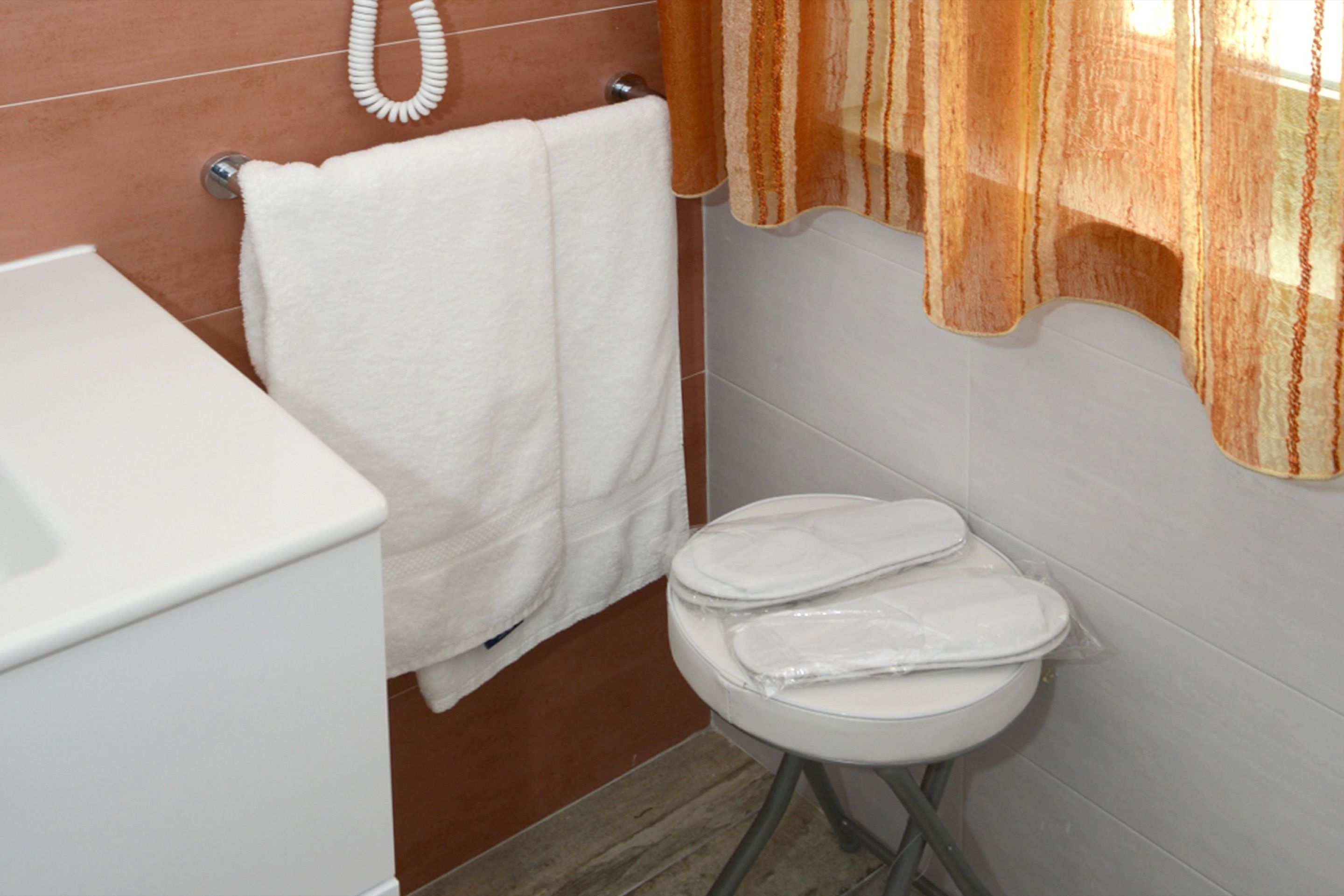 A bathroom with a white toilet, a white sink, and a towel hanging on a rack.