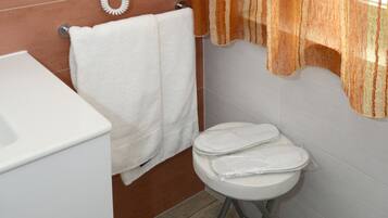 Ein Badezimmer mit einer weißen Toilette, einem weißen Waschbecken und einem Handtuch an einem Wäscheständer.