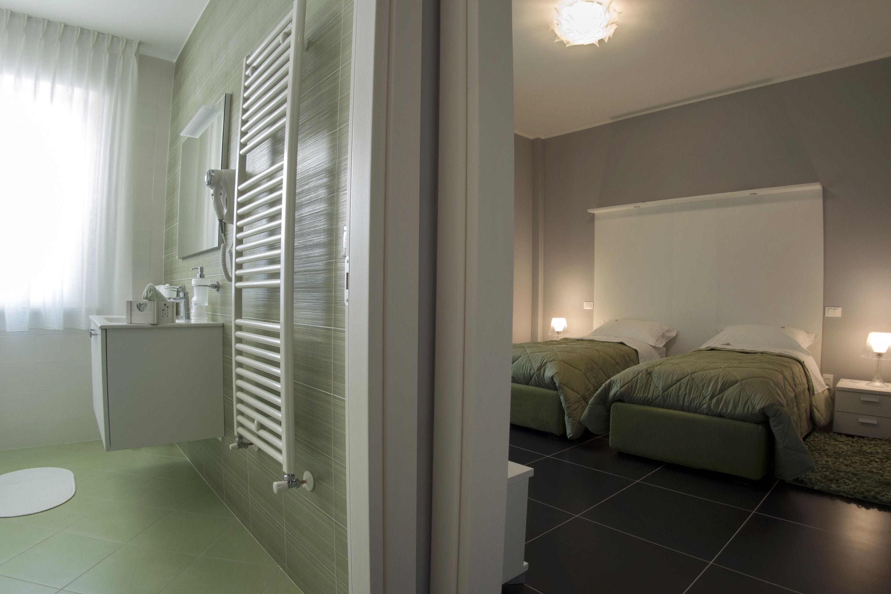 Un bagno moderno con un WC, un lavandino e un porta asciugamani. La stanza presenta uno specchio grande, un porta asciugamani e un termosifone.