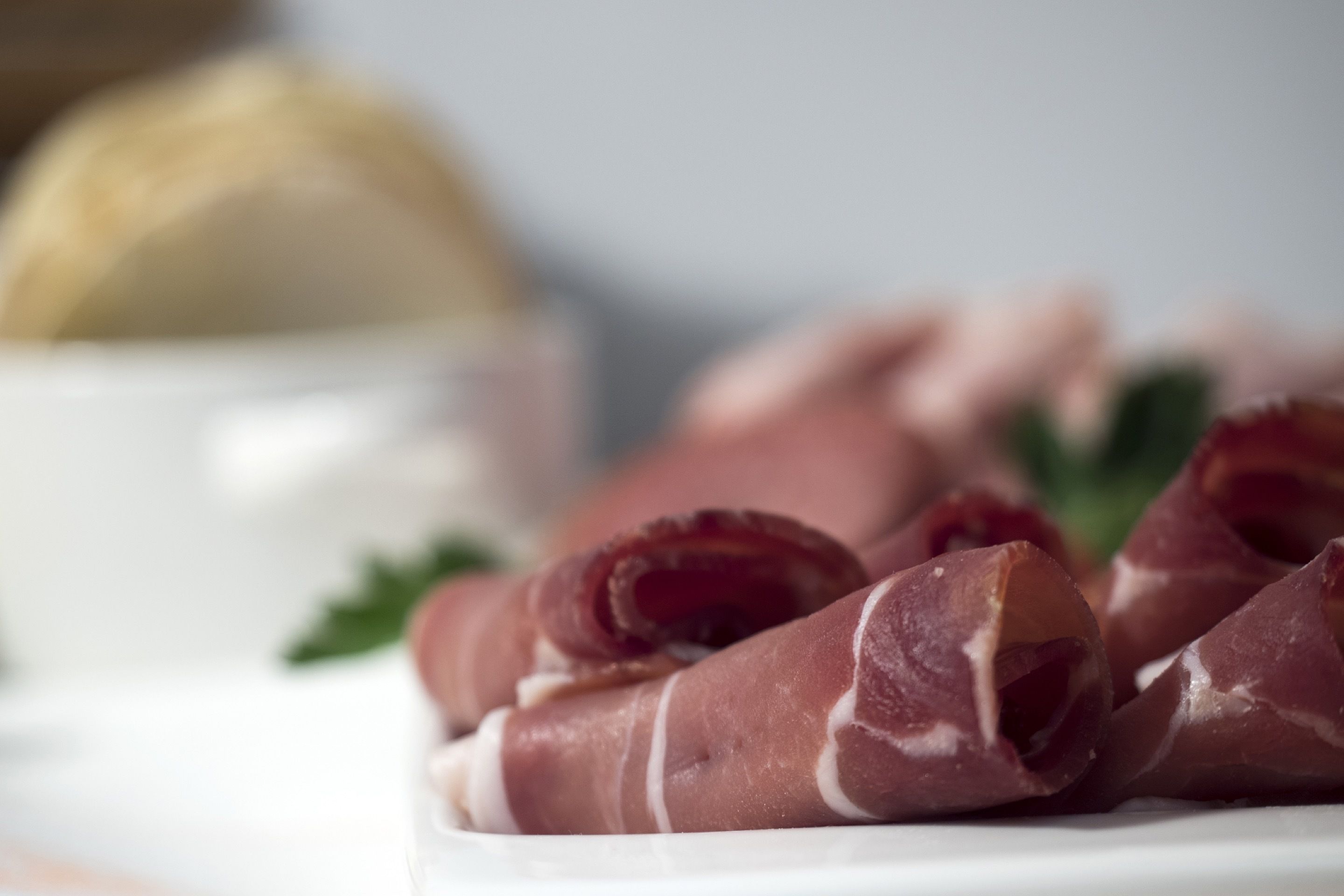 A plate of sliced cured meat with a white background.