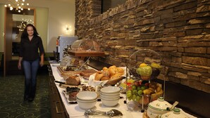A buffet table with various food items and a stone wall in the background. - Viktoria Sölden (Soelden)