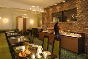 A hotel dining area with multiple tables, chairs, and a buffet counter. - Viktoria Sölden (Soelden)