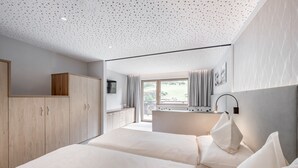 A modern bedroom with a large bed, wooden wardrobe, and a bathroom with a shower and toilet. - Viktoria Sölden (Soelden)