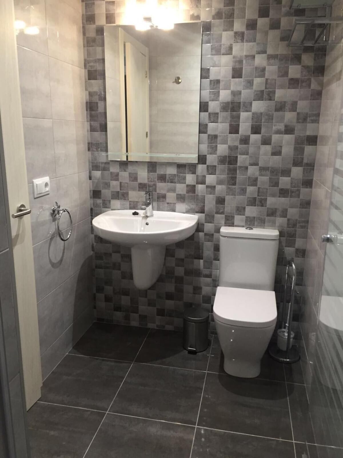 Un bany amb un lavabo, vàter i un mirall sobre el lavabo.