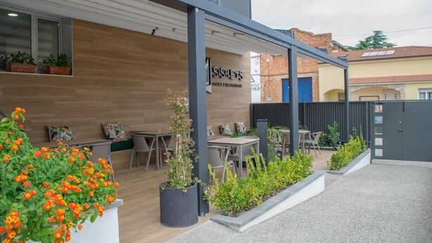 Een modern hotel met buiten zitplaatsen en potplanten.