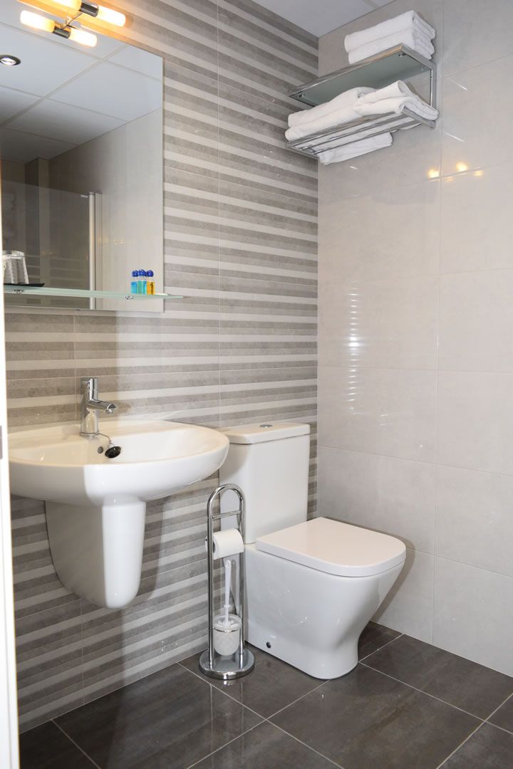 Een moderne badkamer met een wastafel, toilet en handdoekhouder.