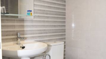 Een moderne badkamer met een wastafel, toilet en handdoekhouder.