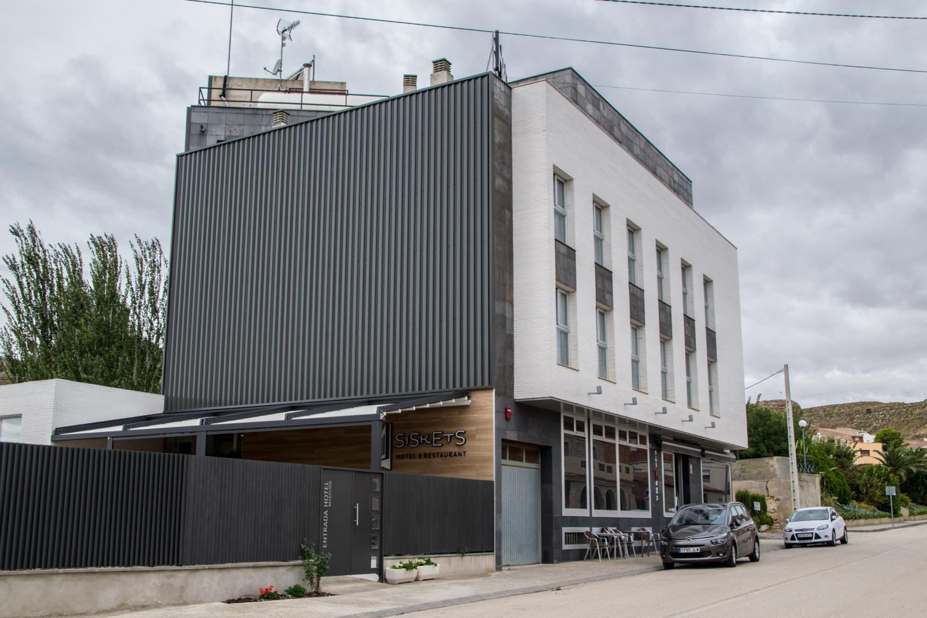 A modern hotel with a large entrance and a covered outdoor seating area.