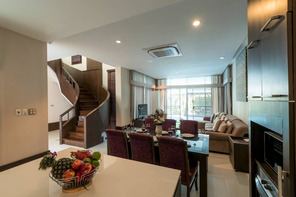 A modern living room with a dining area, a staircase, and a kitchen.