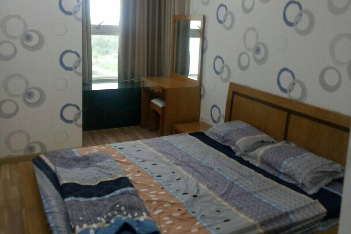 A bedroom with a bed, a desk, and a window.