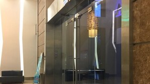 Een moderne lobby met glazen deuren, een trap en een bank.