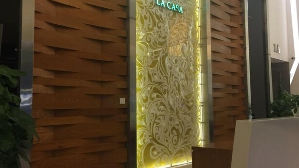 Een moderne hotelreceptie met een houten wandpaneel en een neonbord.
