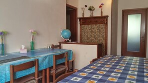 A room with a dining table, chairs, a globe, a vase with flowers, and a door.