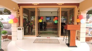 A hotel entrance with a reception desk, a glass door, and colorful balloons.