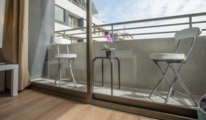 A balcony with two chairs, a small table, and a potted plant. - Altos Alameda (Santiago)