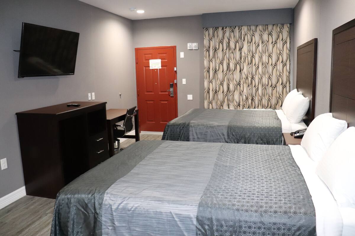 A hotel room with two beds, a TV, a desk, and a wardrobe.