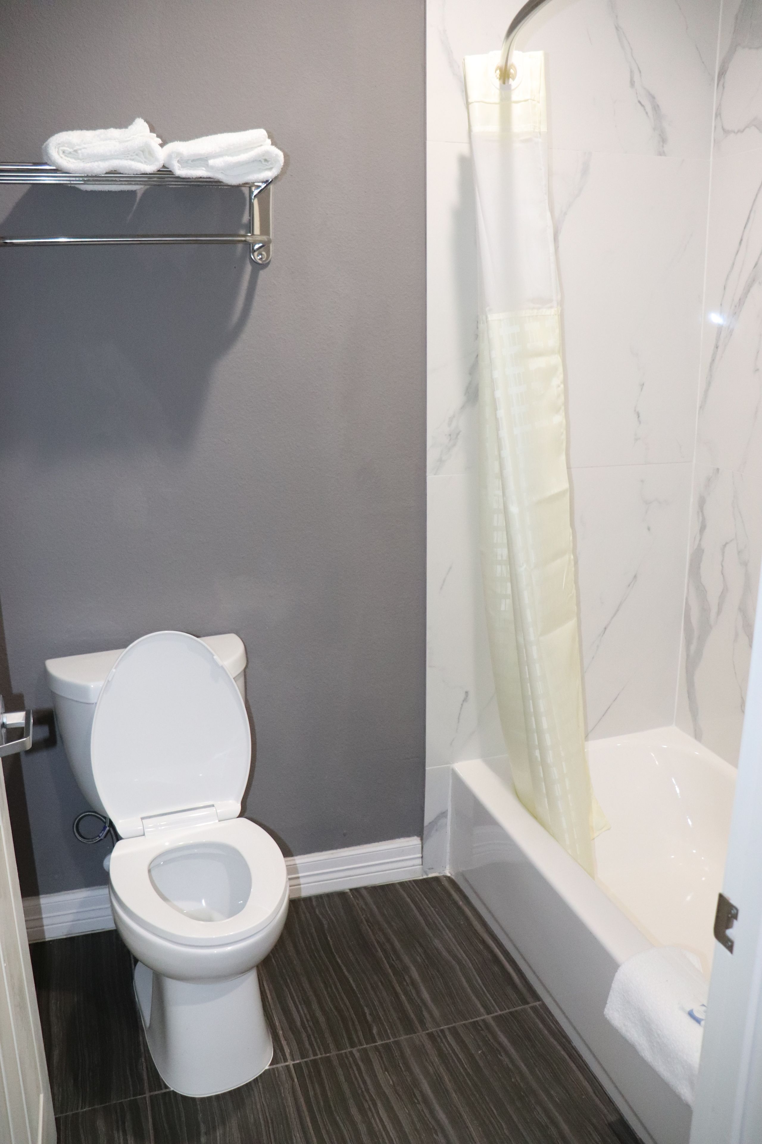 A bathroom with a toilet, a shower with a glass door, and a towel rack.