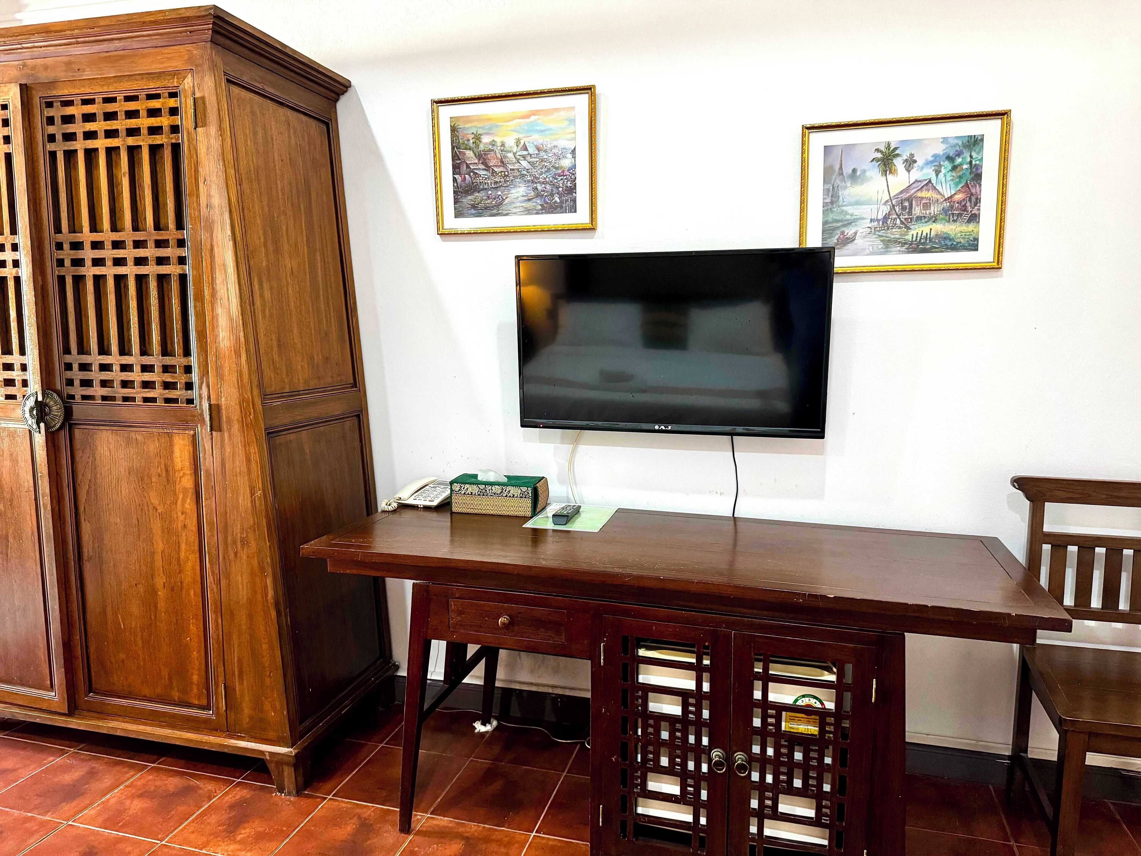 A wooden cabinet with a grid pattern, a television mounted on the wall, and two framed pictures above it.