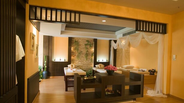 Una sala moderna con piso de madera, una mesa de centro de madera oscura y un sofá con cojines. Se observa una escalera con barandilla que conduce a un nivel superior.