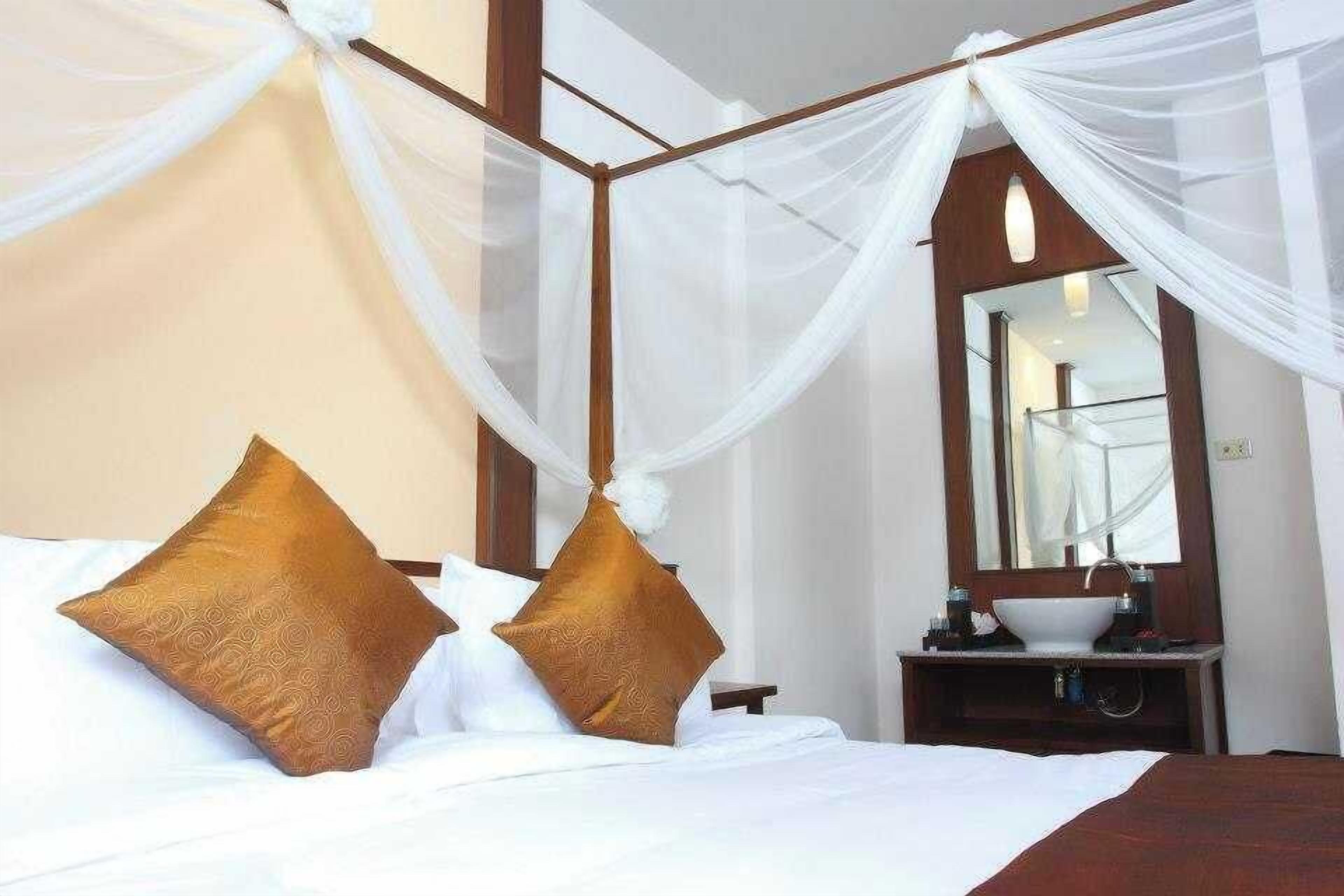 A bedroom with a four-poster bed, a bedside table, a mirror, and a nightstand.