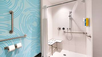 A modern bathroom with a shower, grab bars, and a toilet paper holder.