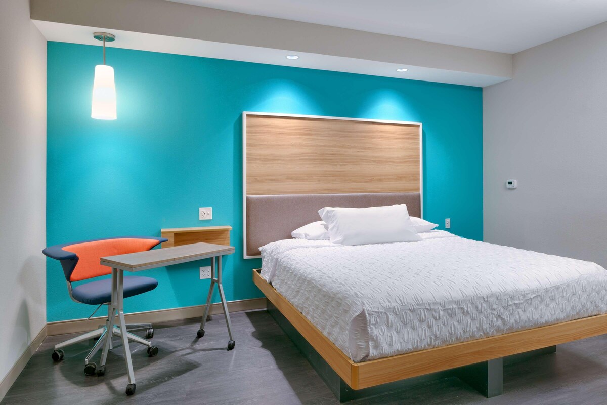 A modern bedroom with a bed, a desk, and a chair.